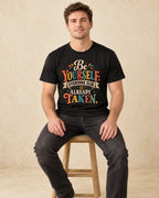 Model seated Be Yourself Everyone Else Is Already Taken T-shirt in Black