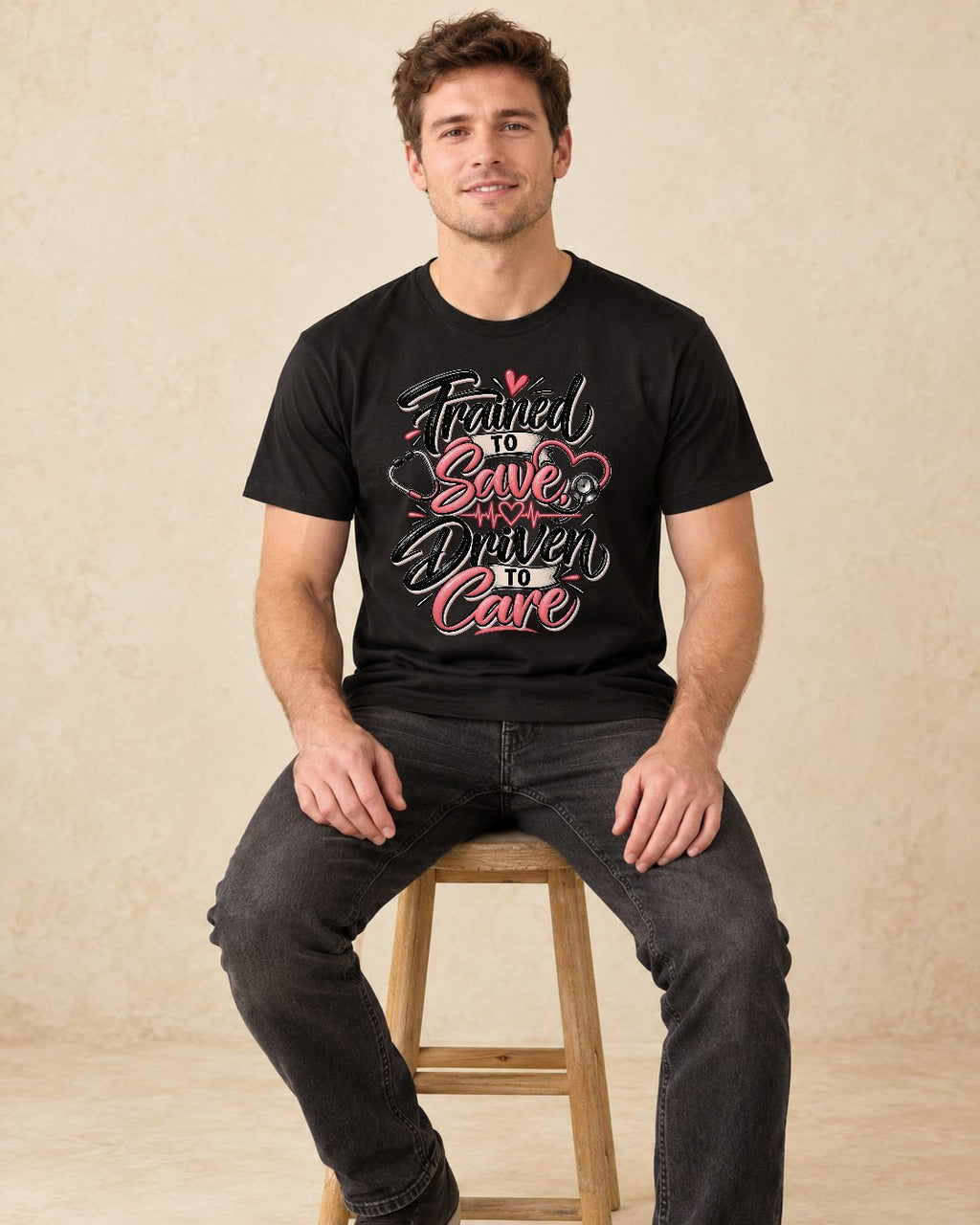 Model seated Trained To Save Driven To Care T-shirt in Black