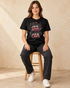 Model seated Trained To Save Driven To Care T-shirt in Black