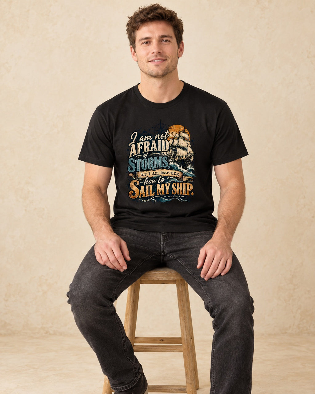 Model seated  I Am Not Afraid Of Storms For I Am Learning How To Sail My Ship T-shirt in Black